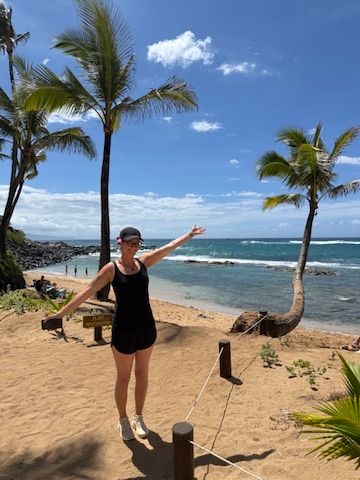 Kris Bradley with arms outstretched on a Maui beach.