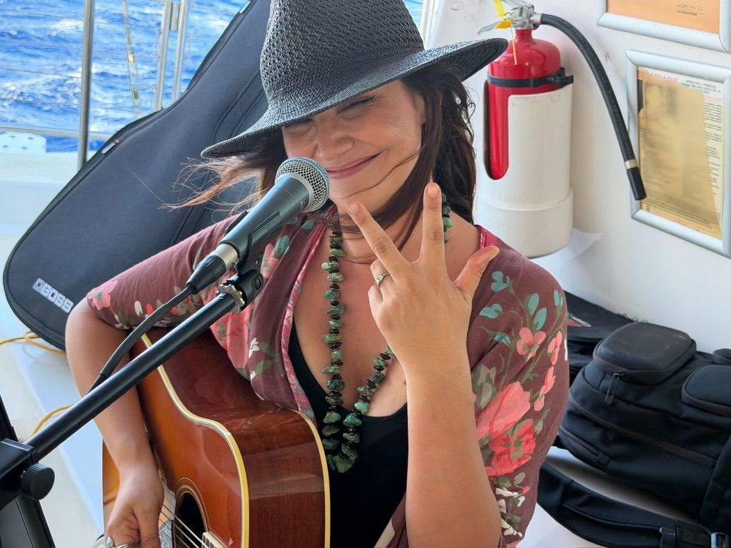 Kris Bradley giving a peace sign during a boat performance.
