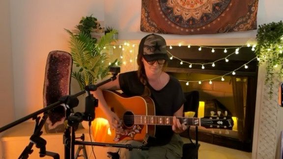 Kris Bradley playing an intimate acoustic set by the fireplace.