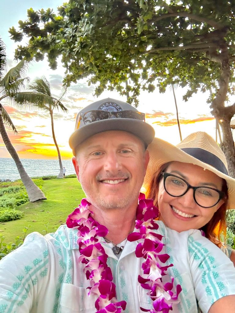 Kris Bradley and her husband wearing leis at sunset on Maui.