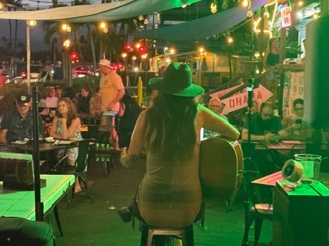 Kris Bradley performing live for a crowd at an outdoor Maui venue in the evening.