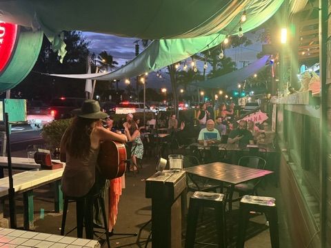 Live performance at an outdoor Maui restaurant patio, string lights overhead.