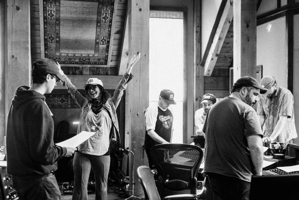 Black and white photo of Kris Bradley celebrating in the recording studio with her production team.