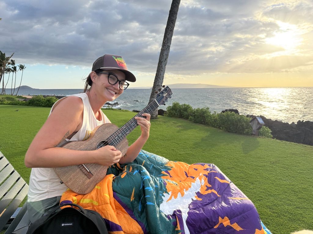 Kris Bradley playing ukulele on the beach.